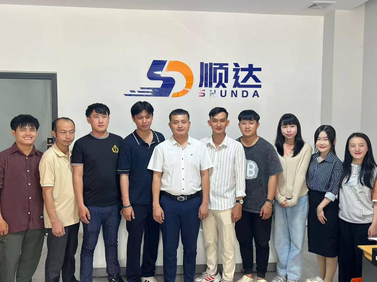 顺达团队在公司标志墙前的集体合影